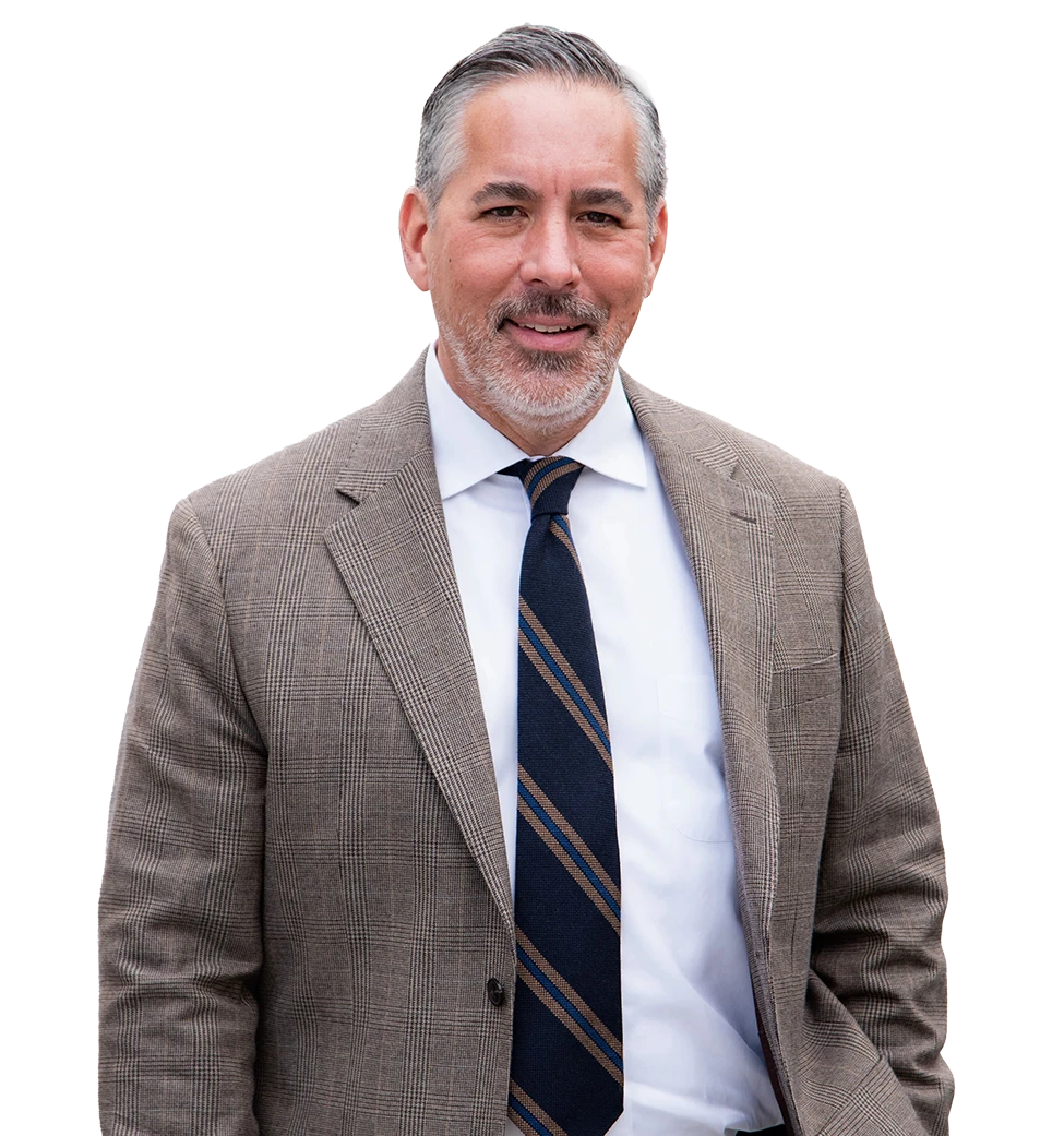 Joaquin, with gray hair and beard, wearing a plaid suit jacket and striped tie.